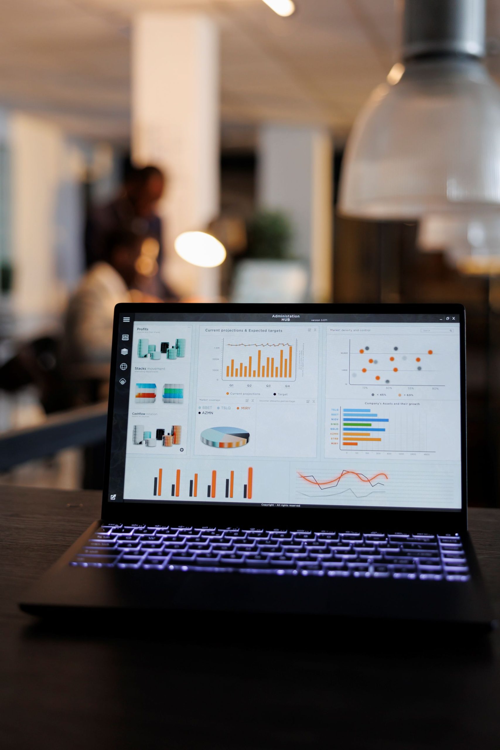 laptop-computer-with-marketing-statistics-graphs-screen-standing-table-startup-office-coworkers-discussing-company-strategy-background-employees-working-overtime-startup-office